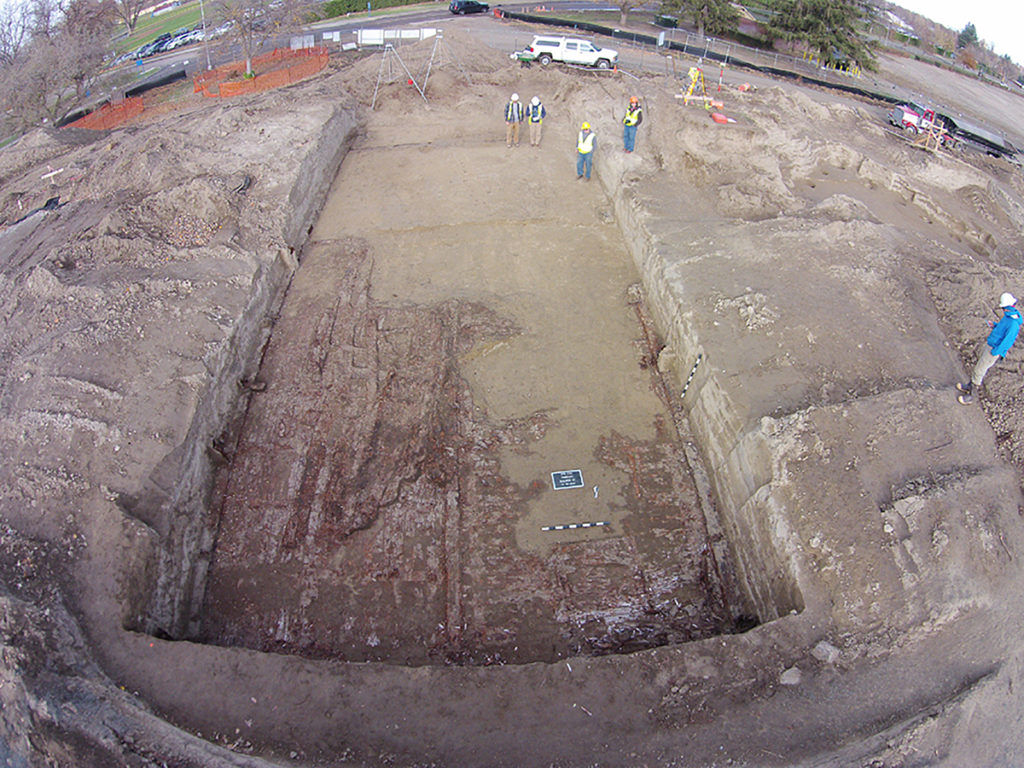 Long rectangular dig site. In the far right, workers can be seen walking.