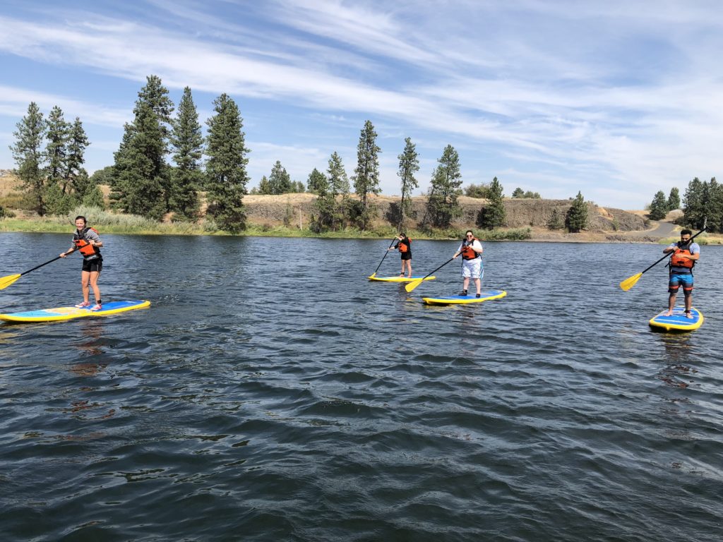 group of students standup paddleboarding on the water