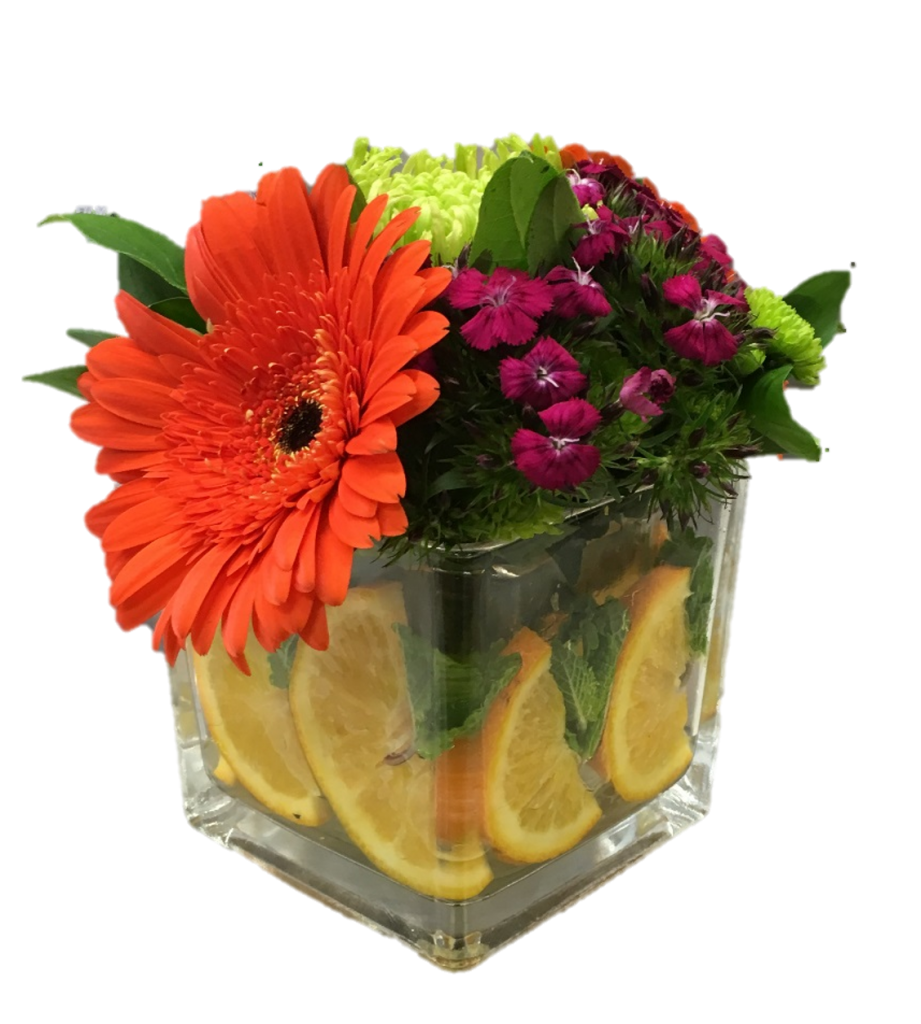 photo flowers in a square vase. There is an medium sized orange flower to the left and a small amount of dark pink flowers to the right. At the bottom of the vase are orange slices