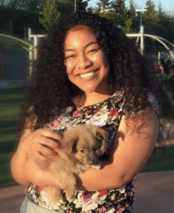 photo of Angela Vakauta smiling holding a dog
