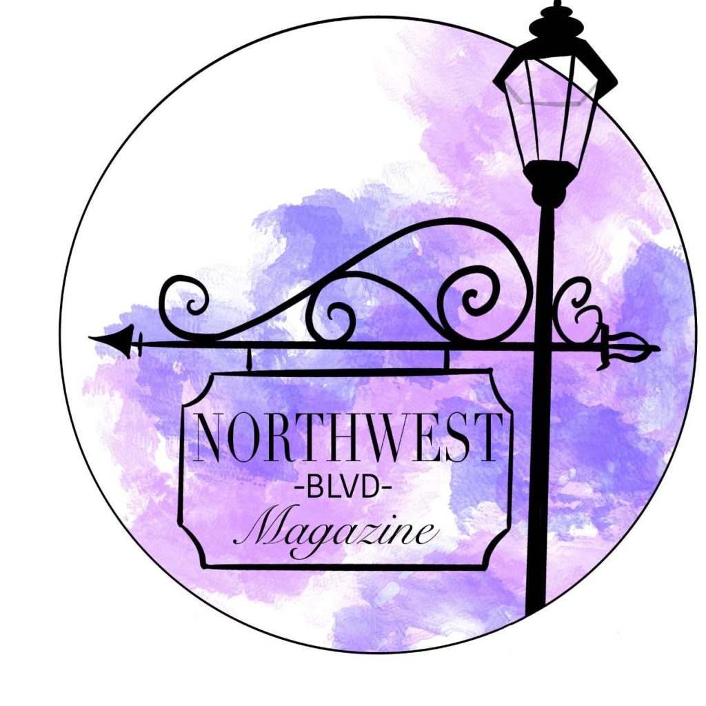 photo of Northwest Boulevard Magazine logo. Its a sign that features the name of magazine hanging from a black sign. The background is water color shades of purple. It is a circle.