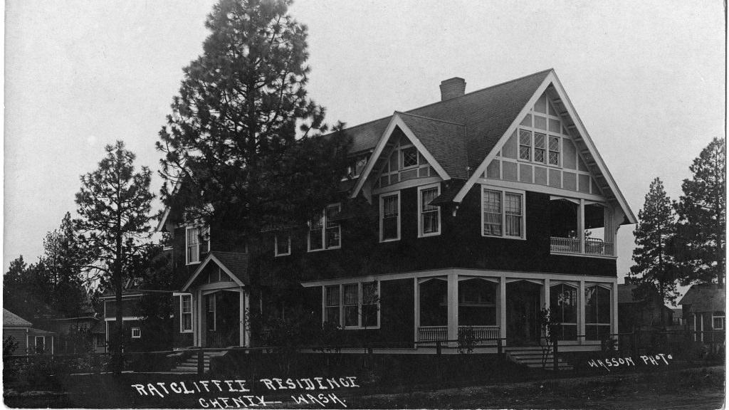 view of Ratcliffe House. The photo is in black and white and show the house from an angle. The house features one right side with a large top window and a deck. The left side has another entrance