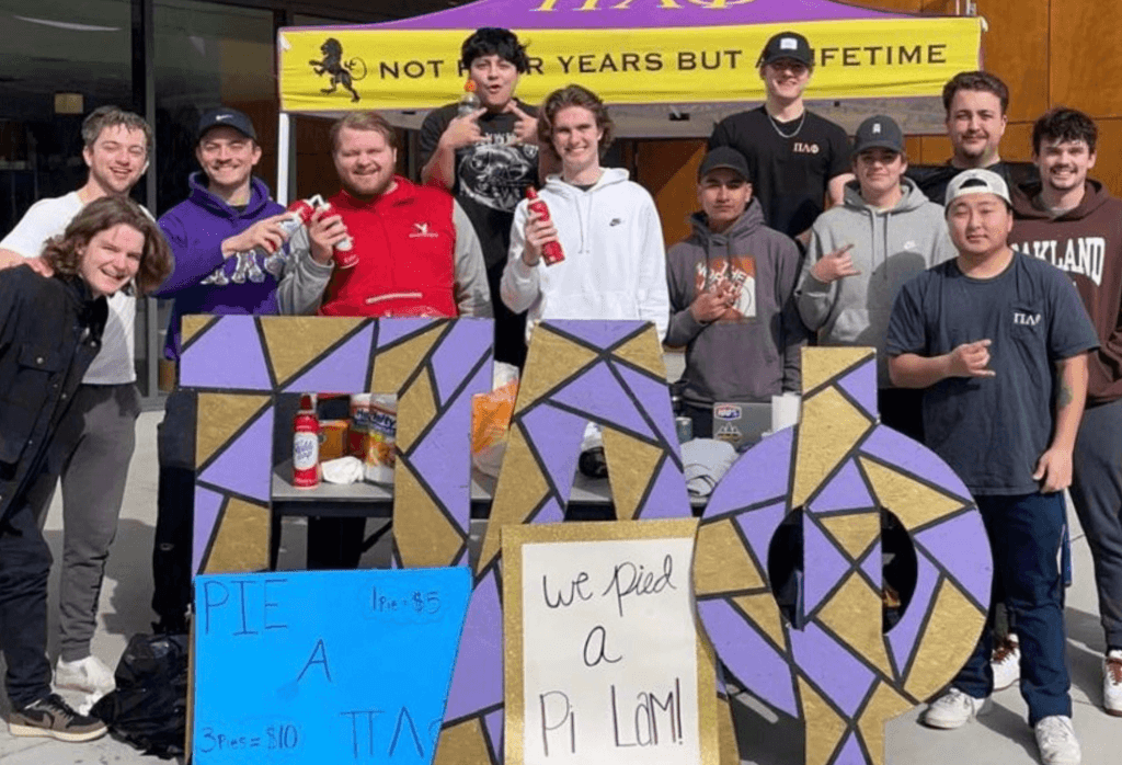 Group of fraternity students in front of PUB with their greek letters during the day