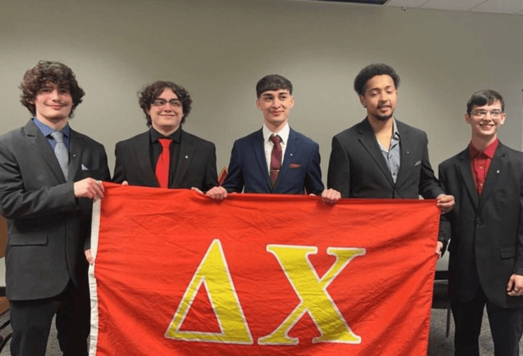 Fraternity students hold up their fraternity banner