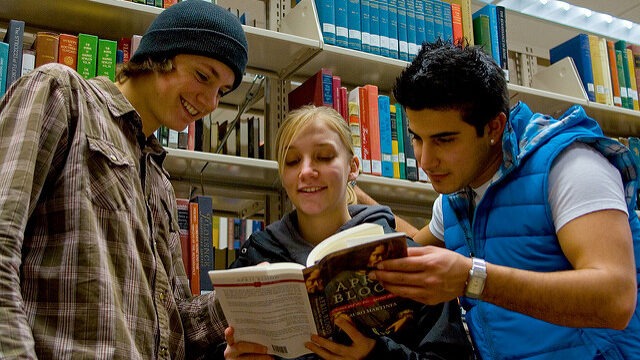 Students reading a book together. They are at the EWU Library